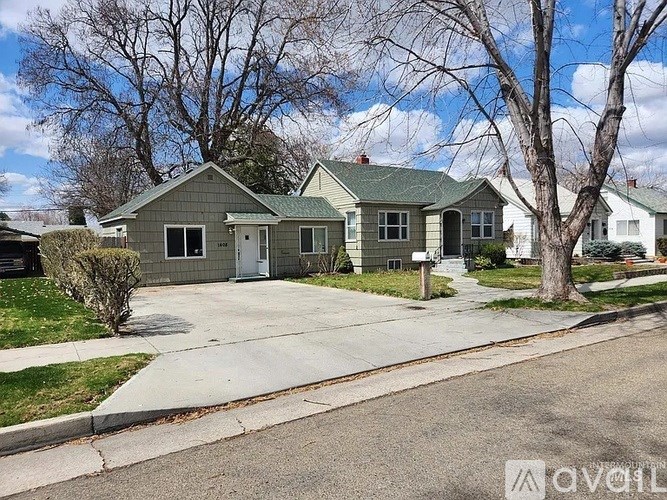 A house with a grey roof and white door is surrounded by trees.