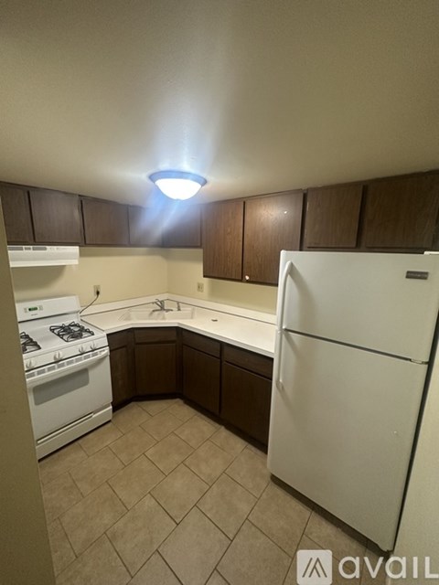 A kitchen with a white refrigerator, white stove, and brown cabinets.