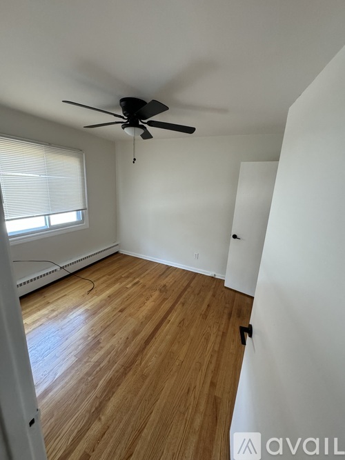 A room with a ceiling fan and wooden flooring.