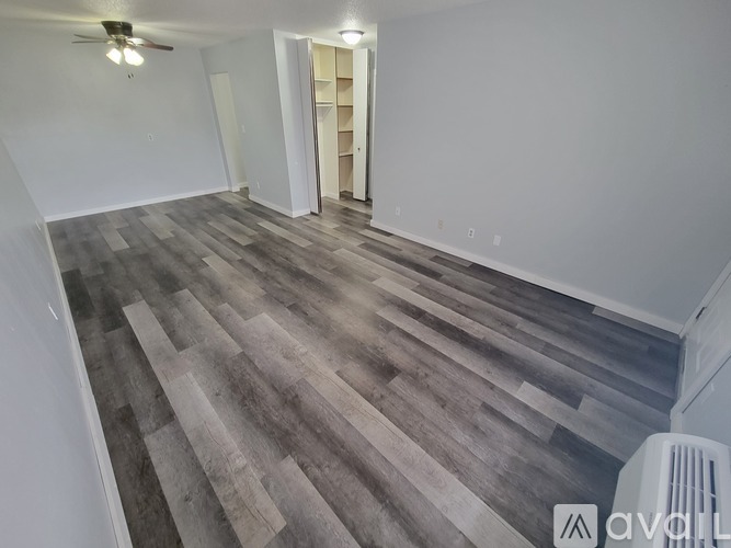 A room with wooden flooring and a white refrigerator.