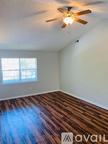 A room with a ceiling fan and wooden flooring.