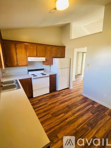 A kitchen with white appliances and wooden cabinets.