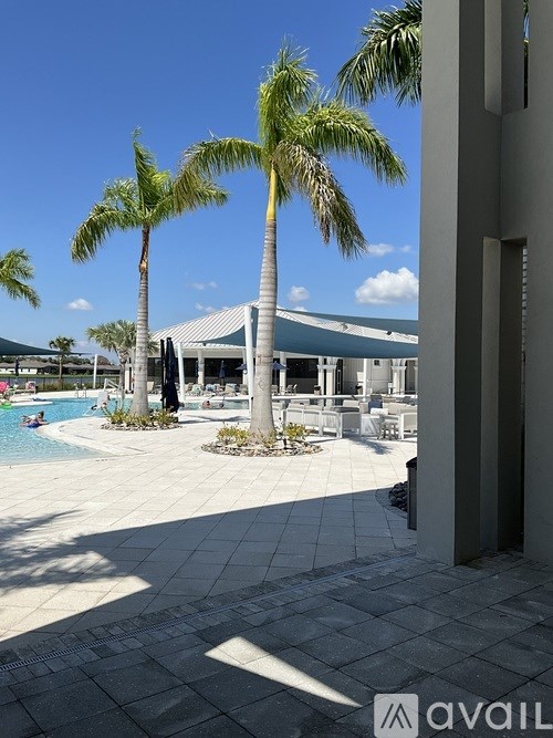 A pool area with palm trees and a building in the background.