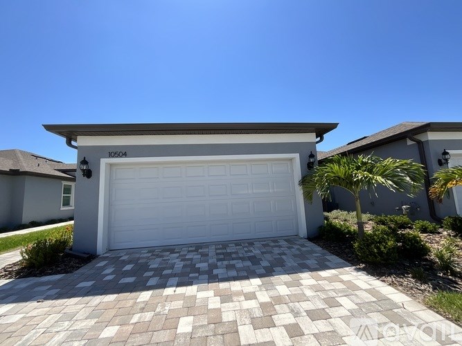 A house with a white garage door and a driveway made of tiles.