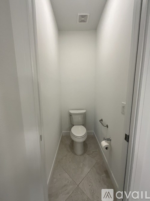 A white toilet in a small bathroom with tiled flooring and walls.