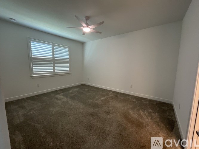 A room with a ceiling fan and a window with blinds.