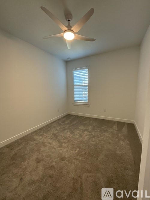 A room with a ceiling fan and a window with blinds.