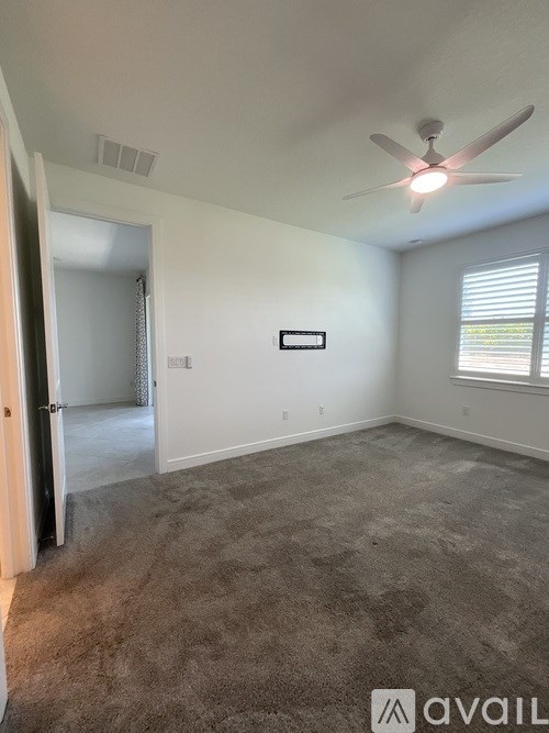 A room with a carpeted floor and a ceiling fan.