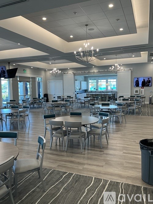 A large room with tables and chairs and a screen tv.