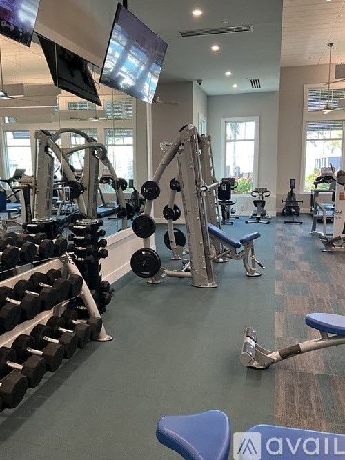 A gym with a variety of equipment including dumbbells, weight plates, and a bench.