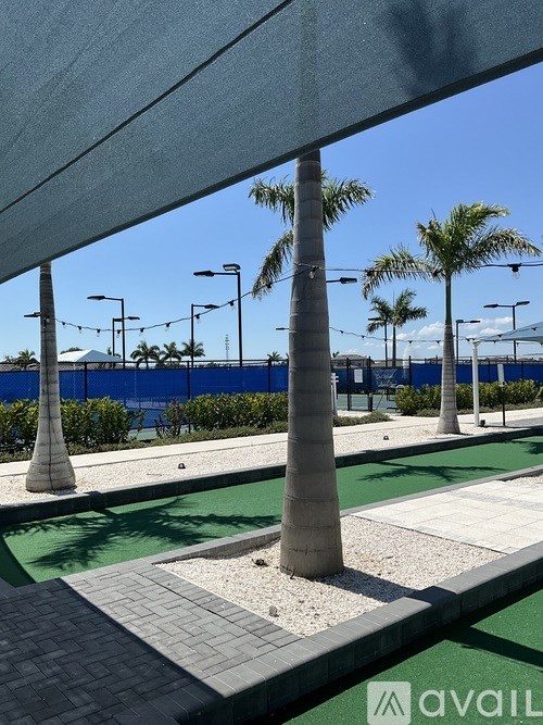 A miniature golf course with palm trees and a blue sky.
