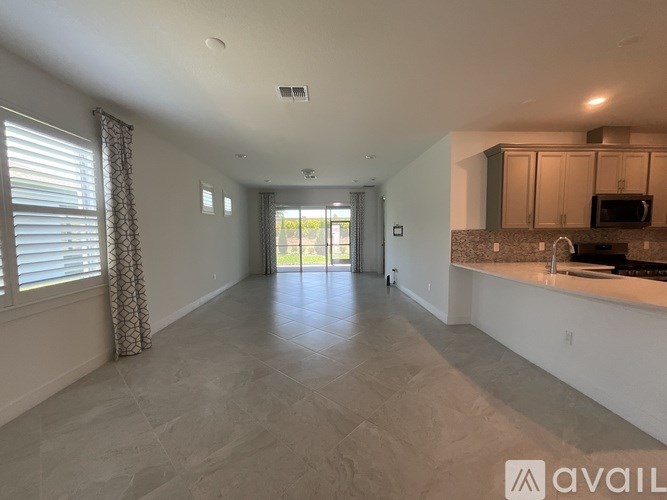 A spacious living room with a kitchen area in the background.