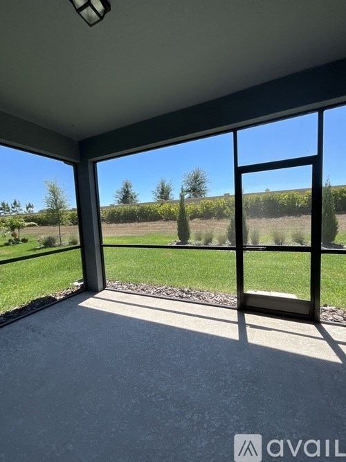A room with a large window overlooking a grassy field.