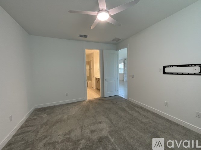 A room with a fan and a carpeted floor.