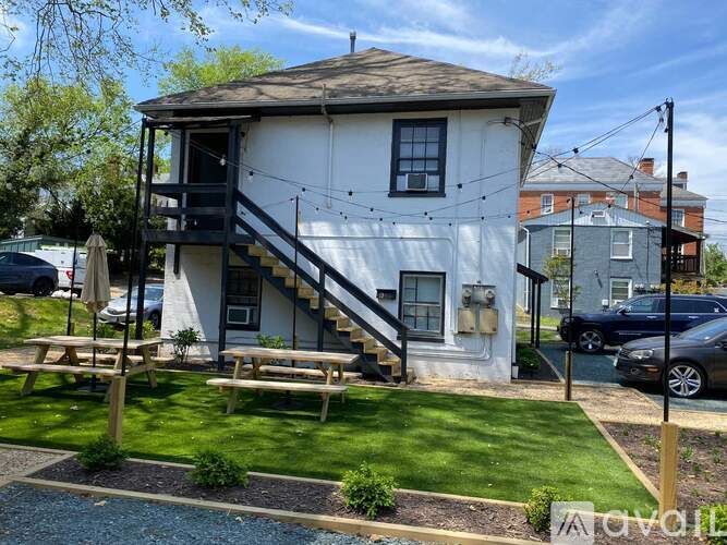 A white house with a black staircase and a picnic table in front.