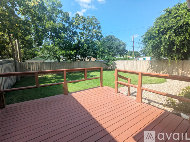 A wooden deck with a railing and a grassy area in the background.