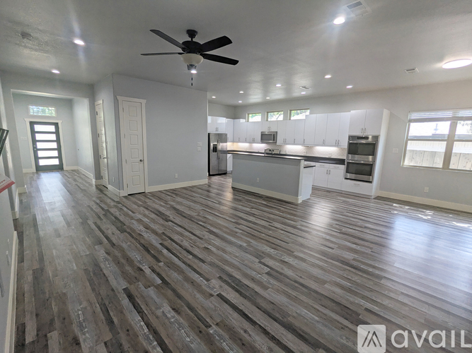 A spacious room with a ceiling fan and wooden flooring.