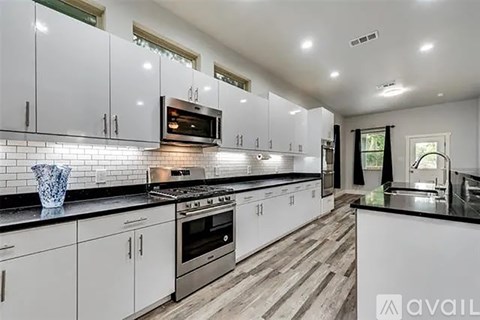 A kitchen with white cabinets and black countertops.
