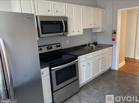 A kitchen with white cabinets and a stainless steel refrigerator.