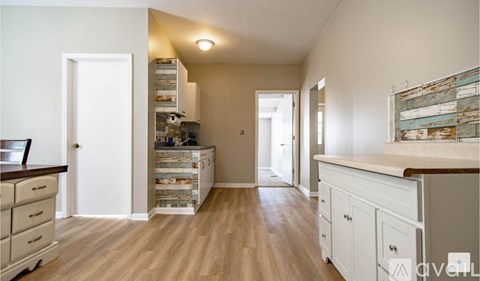 A kitchen with white cabinets and a wooden floor.