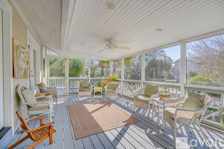 A sunny day on a white wooden porch with a rug and chairs.