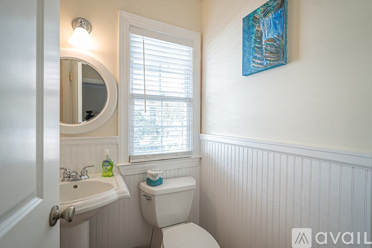 A bathroom with a toilet, sink, and a mirror.