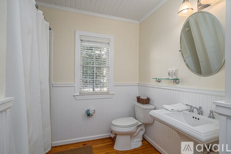 A bathroom with a toilet, sink, and window.