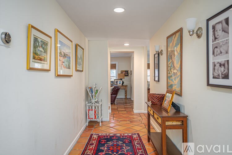 A hallway with a rug on the floor and pictures on the wall.