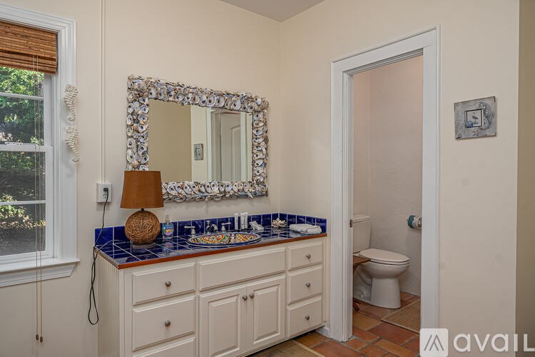 A bathroom with a mirror, a lamp, and a toilet.