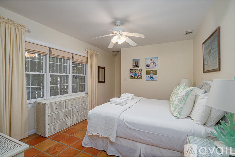 A bedroom with a bed, dresser, and a ceiling fan.
