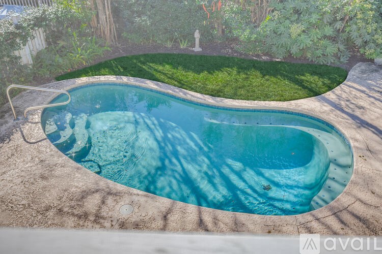 A small, round, blue pool with a white fence and green grass in the background.