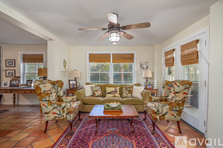 A living room with a couch, chairs, and a rug.