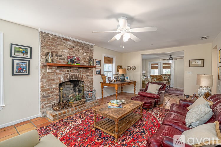 A living room with a brick fireplace and a red rug.