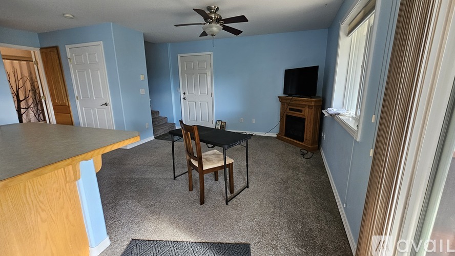 A room with a ceiling fan and a wooden cabinet.