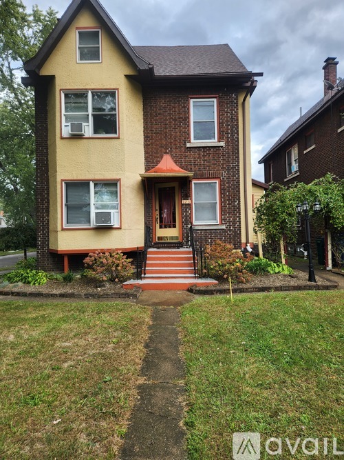 A two-story house with a red door and a small porch.