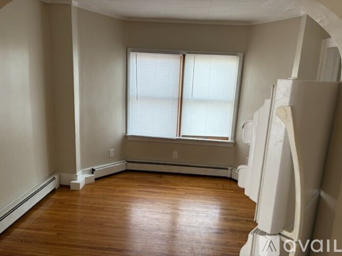 A room with wooden floors and a window with blinds.