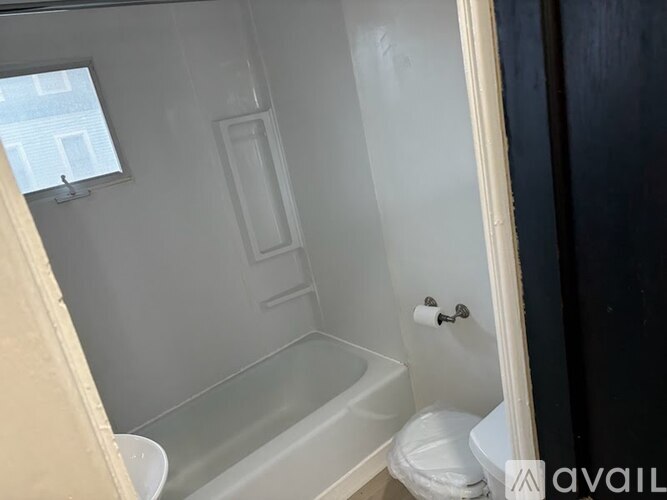 A bathroom with a toilet, tub, and window.