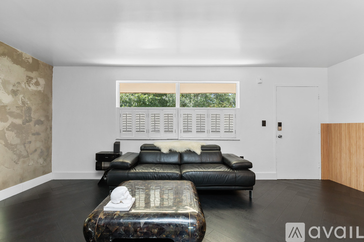 A bedroom with a black leather sofa and a bed with a patterned cover.