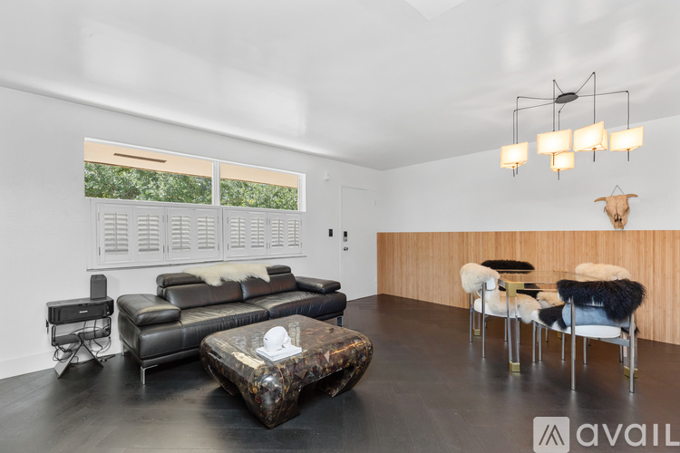 A living room with a black leather couch and a wooden coffee table.
