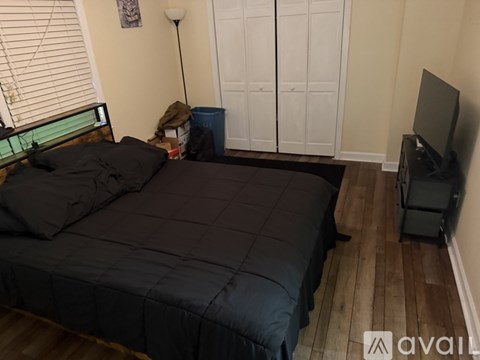 A bedroom with a bed, a TV, and a lamp.