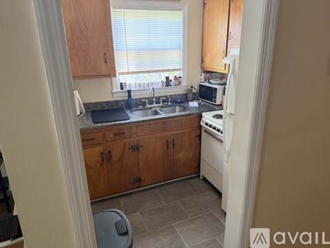 A kitchen with wooden cabinets and a window with blinds.