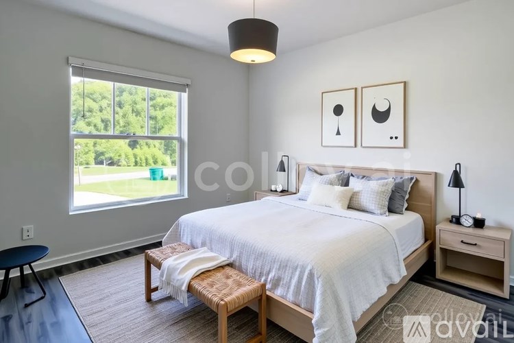 A bedroom with a large bed, a bench, and a window overlooking a green area.