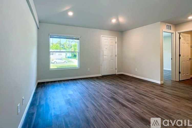 A spacious room with wooden flooring and white walls.