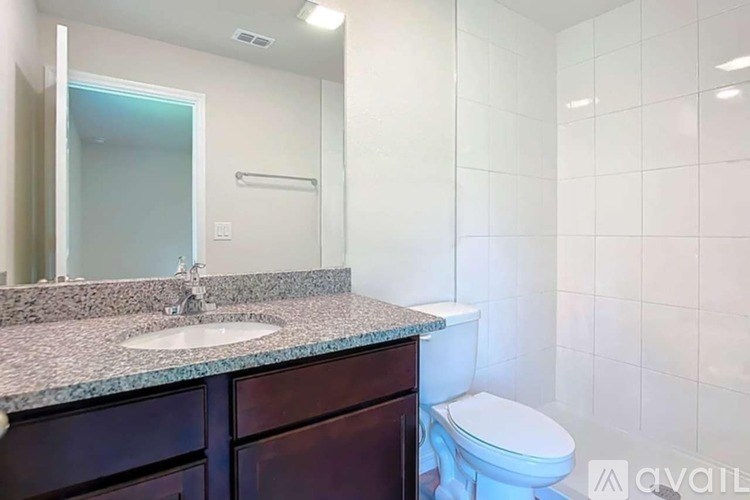 A bathroom with a toilet, sink, and mirror.