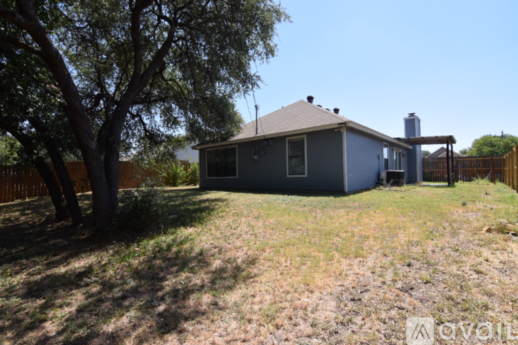 A spacious room with a ceiling fan and light, hardwood floors, and a large window.