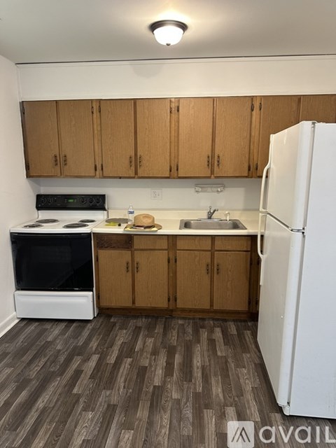 A kitchen with a white fridge, black stove and wooden cabinets.