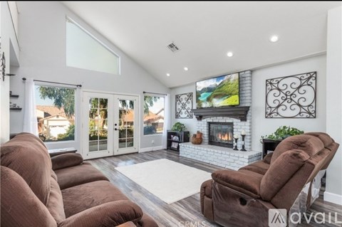 A living room with a fireplace and a television mounted above it.