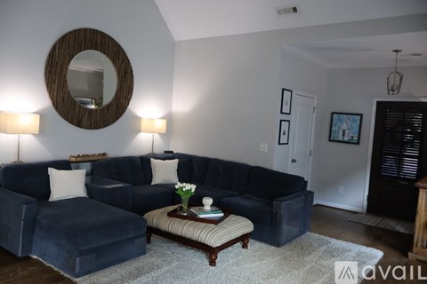 A living room with a dark blue couch and a round mirror on the wall.