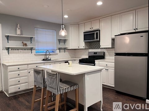 A kitchen with white cabinets and a black and white striped bar stool.