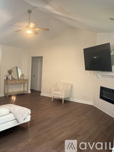 A living room with a white couch and a flat screen TV mounted on the wall.